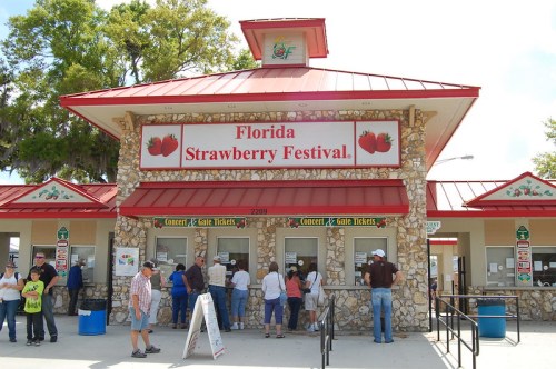 Ticket booth at the Florida Strawberry Festival, with people purchasing tickets and a festive building design.