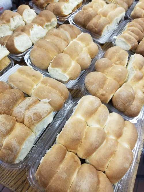 A close-up of multiple trays filled with soft, golden-brown dinner rolls arranged neatly.