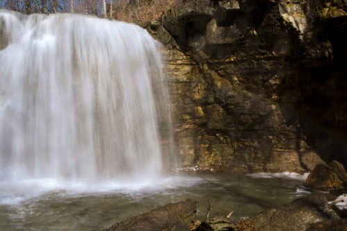 A serene waterfall cascading over rocky cliffs into a calm pool below, surrounded by nature.