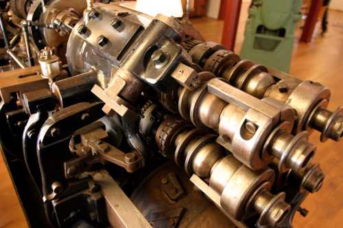 Close-up of a vintage engine's mechanical components, showcasing gears and camshafts in a workshop setting.