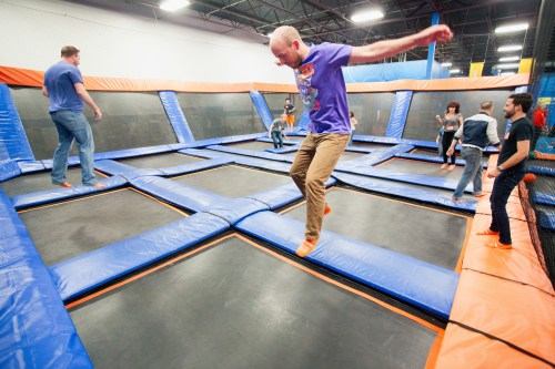 A group of people jumping on trampolines in a vibrant indoor trampoline park.