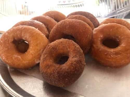 A platter of assorted donuts, including glazed and cinnamon sugar varieties, arranged neatly on a silver tray.