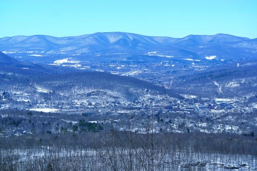 A snowy valley surrounded by mountains under a clear blue sky, showcasing a serene winter landscape.
