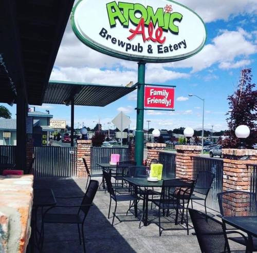 Outdoor seating area of Atomic Ale Brewpub & Eatery, featuring tables and a sign that reads "Family Friendly!"