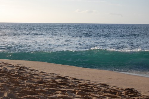 A serene beach scene with gentle waves lapping at the shore under a clear sky.
