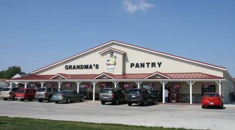 A large building with the sign "Grandma's Pantry," featuring a red roof and parked cars in front.