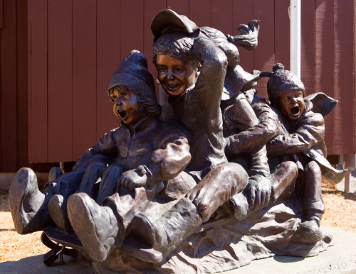 A bronze sculpture of three joyful children playing together, capturing a moment of fun and laughter.