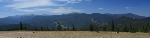 Panoramic view of a mountainous landscape with green forests and a clear blue sky.