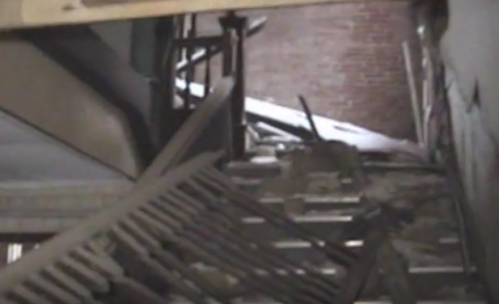 A view of a damaged interior with debris and broken structures, suggesting neglect or disrepair.