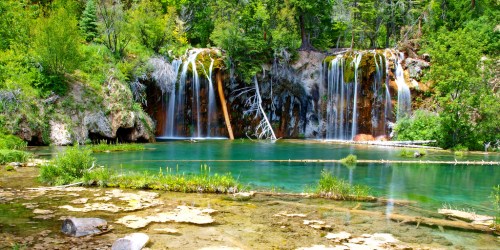 A serene landscape featuring cascading waterfalls surrounded by lush greenery and a clear blue pool.