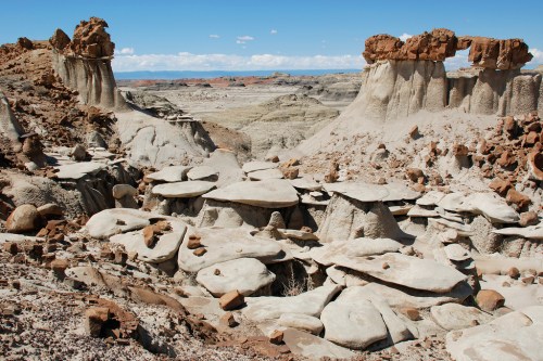A rugged landscape featuring unique rock formations and mesas under a clear blue sky.