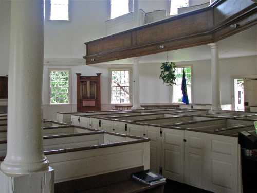 Interior of a church featuring wooden pews, tall windows, and a balcony overlooking the main area.