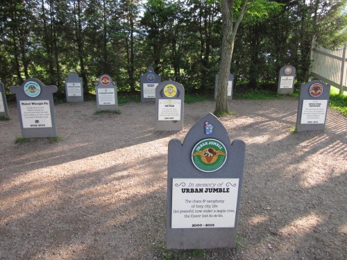 A memorial site with gravestone-like markers honoring various animals, surrounded by trees and gravel paths.