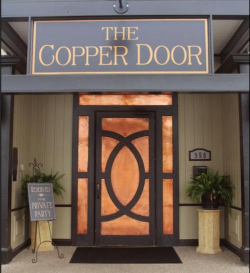 Entrance of The Copper Door featuring a copper-accented door and a sign for a private party reservation.