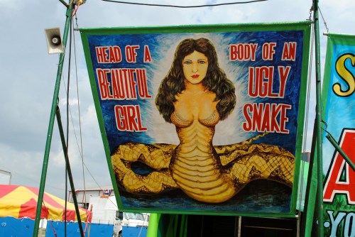 A colorful banner depicting a woman’s head on a snake's body, with the text "Head of a Beautiful Girl, Body of an Ugly Snake."