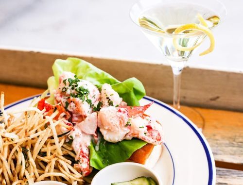 A lobster roll with lettuce, served with fries and a martini garnished with a lemon twist.
