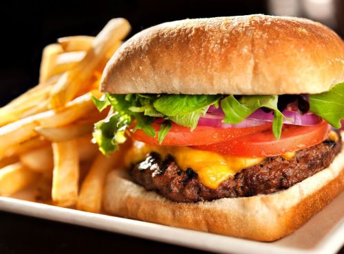 A juicy cheeseburger with lettuce, tomato, and onion, served with a side of crispy French fries.