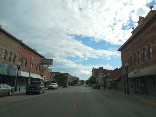 A quiet downtown street lined with historic buildings under a partly cloudy sky.
