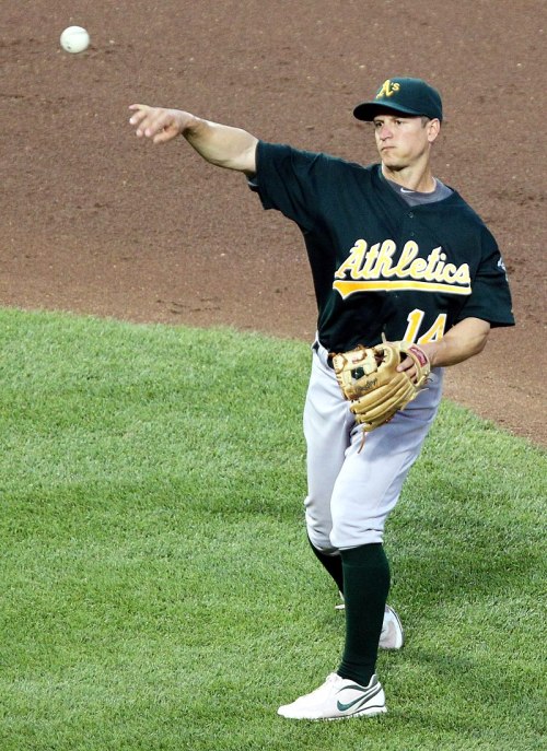 A baseball player in a green and yellow jersey throws a ball from the infield during a game.
