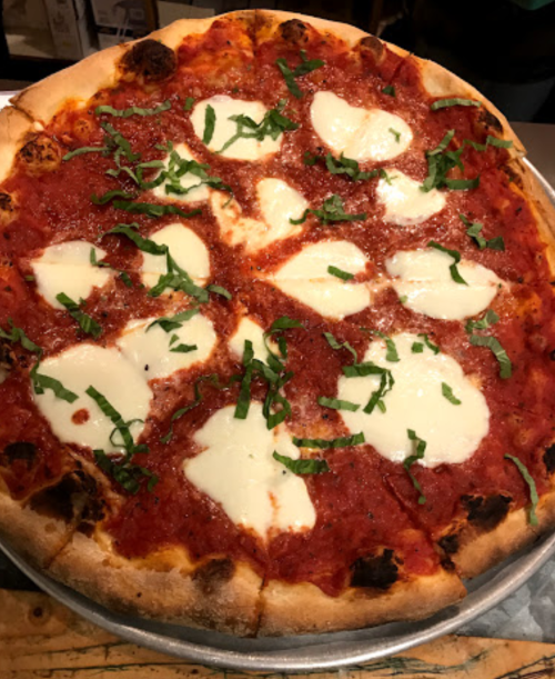 A freshly baked pizza topped with tomato sauce, mozzarella cheese, and fresh basil leaves.
