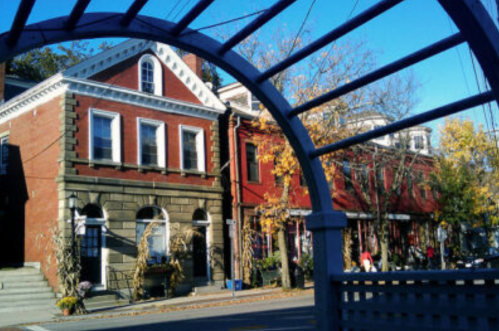 A charming street scene featuring historic brick buildings and autumn foliage under a clear blue sky.