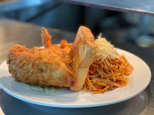 A plate featuring fried chicken, toast, and a serving of spaghetti with marinara sauce and cheese.