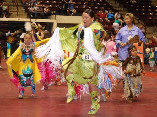 A group of dancers in colorful traditional attire perform at a cultural event, showcasing vibrant costumes and movements.