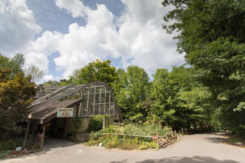 A greenhouse labeled "Green Class Asia" surrounded by lush greenery and trees under a partly cloudy sky.