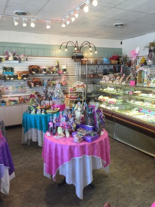 A colorful candy shop interior with decorated tables, showcasing various sweets and treats under bright lighting.