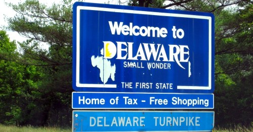 Welcome sign for Delaware, featuring "The First State" and promoting tax-free shopping.