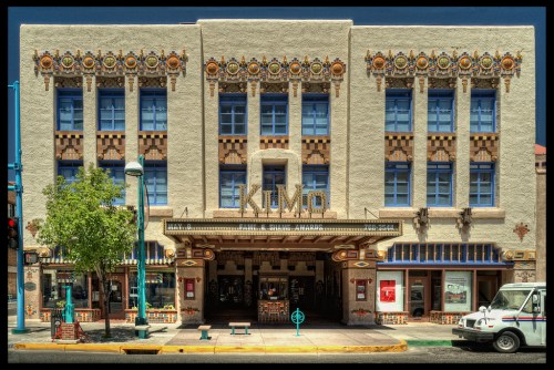 Historic theater building with ornate architectural details and colorful decorations, featuring large windows and a marquee.