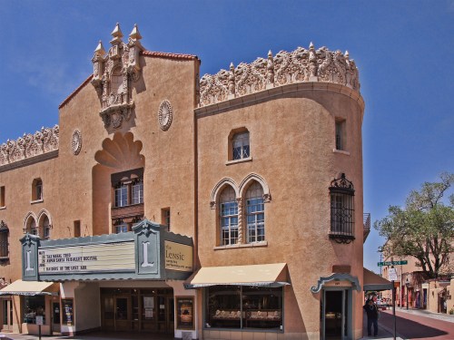 Historic theater building with ornate architecture, featuring a marquee and decorative elements under a clear blue sky.