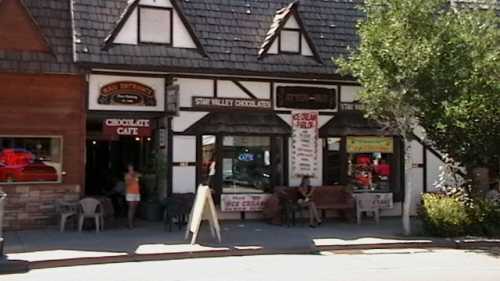 A charming storefront featuring a chocolate cafe and ice cream shop, with outdoor seating and signage.