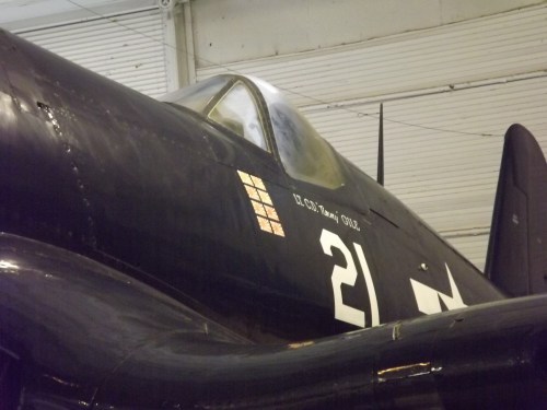 Close-up of a vintage military aircraft with the number 21 and insignia, displayed indoors.