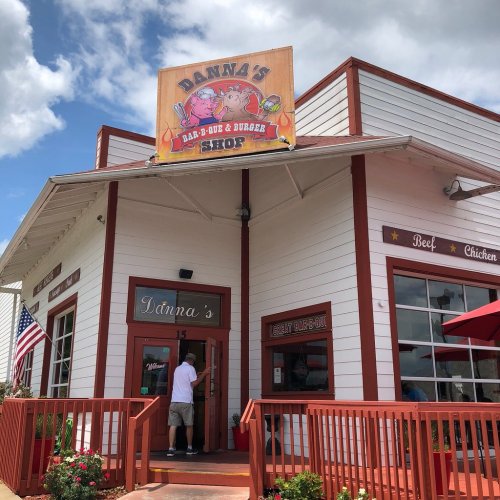 Exterior of Danna's Bar-B-Q & Burger Shop, featuring a sign and red accents, with a person entering the restaurant.