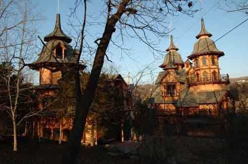 Two ornate, turreted buildings surrounded by trees, bathed in warm sunlight against a clear blue sky.