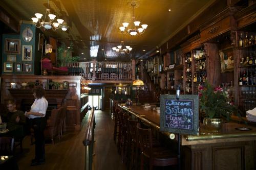 A cozy restaurant interior with wooden decor, a long bar, and warm lighting, featuring tables and a welcoming sign.