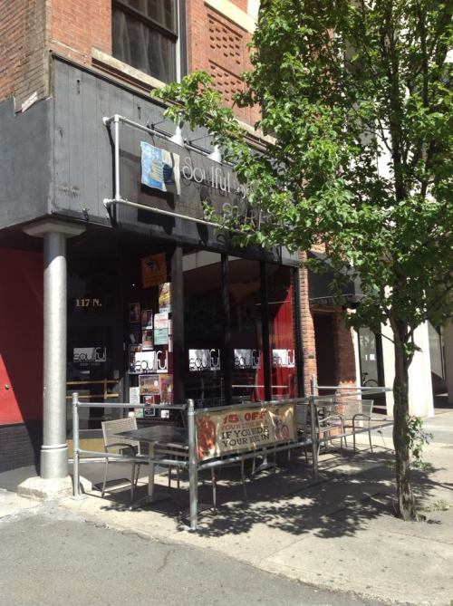 A street view of a restaurant with outdoor seating and a tree in front, featuring a sign that reads "Soulful."