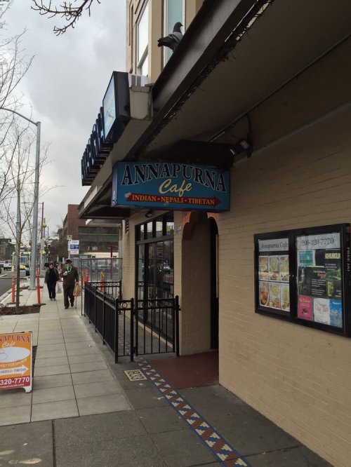 Sign for Annapurna Cafe, featuring Indian, Nepalese, and Tibetan cuisine, located on a city street.