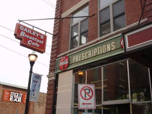 Signage for Gailey's Breakfast Cafe and a prescription store, with a Coca-Cola logo, on a brick building.