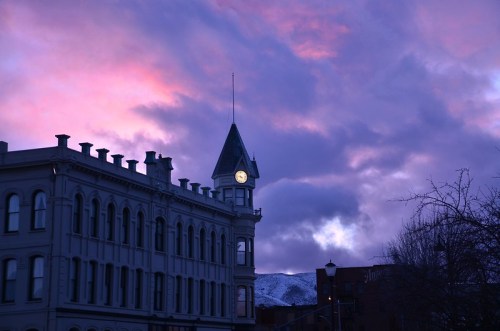 A historic building with a clock tower against a vibrant purple and pink sunset sky.