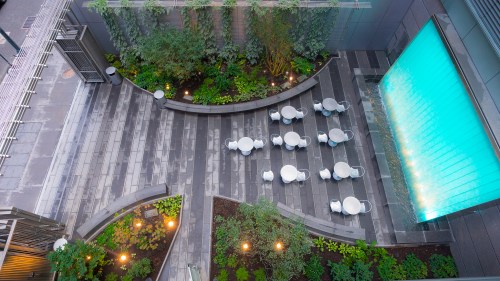 Aerial view of a modern outdoor space with seating, greenery, and a water feature.