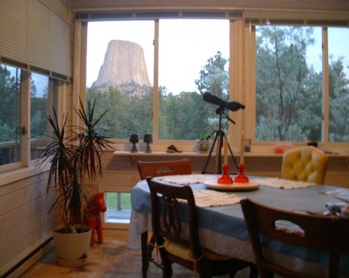 A cozy dining area with a table and chairs, featuring a view of a large rock formation through a window.