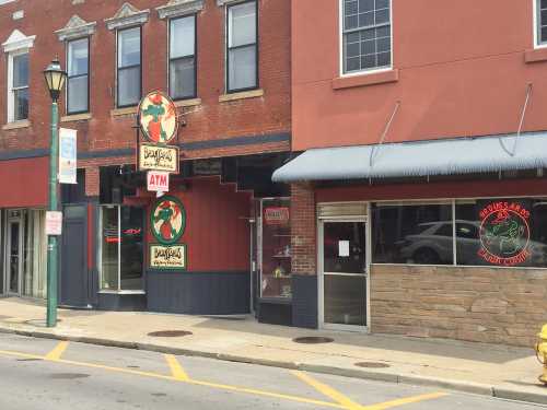 A storefront with a sign for "Bonsai's" and an ATM, featuring a red brick facade and large windows.