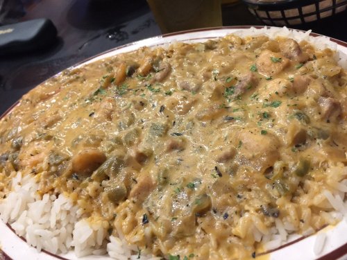 A plate of creamy chicken and rice, garnished with herbs, served on a white dish.