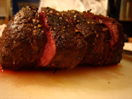 A perfectly cooked roast beef with a crusty exterior and juicy pink interior, resting on a cutting board.