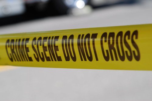 Yellow police tape reading "CRIME SCENE DO NOT CROSS" at a crime scene.
