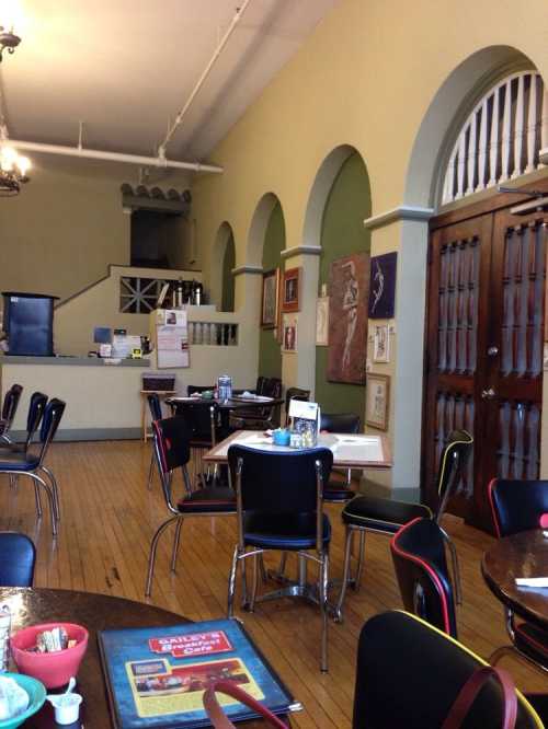 Interior of a cozy restaurant with wooden floors, arched doorways, and tables set for dining.