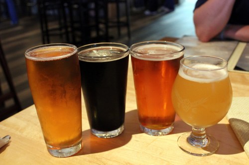 Four glasses of different types of beer on a wooden table, showcasing a variety of colors and styles.