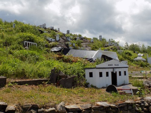 A hillside covered in small white structures and greenery, resembling a miniature village or ghost town.